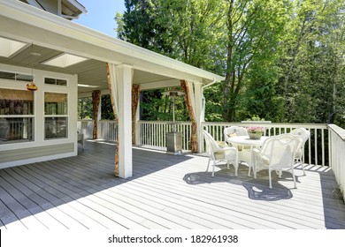 Beautiful Backyard Deck With White Wicker Table Set.