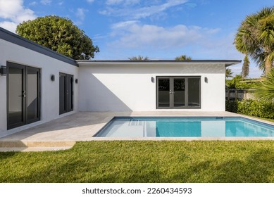 Beautiful backyard of elegant and modern house in the Nautilius neighborhood of Miami Beach, swimming pool, short grass, trees and tropical plants, blue sky in the background - Powered by Shutterstock