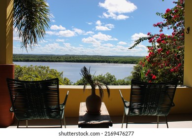 a beautiful balcony with chairs side by side and overlooking a beautiful landscape with forest and river