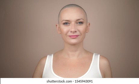 beautiful bald woman holds a pink ribbon in her hands. gentle pastel background.