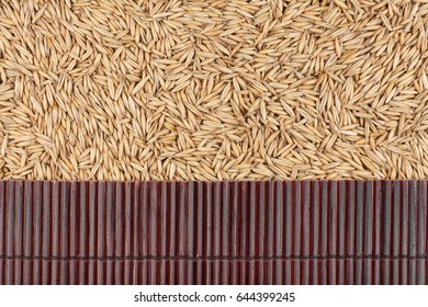Beautiful bamboo mat on oat grains as agricultural background. View from above