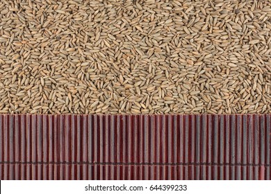 Beautiful bamboo mat on rye grains as agricultural background. View from above