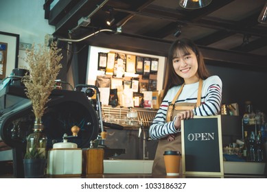 Beautiful barista holding blackboard with word"open" and smiles - Powered by Shutterstock