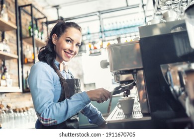 Beautiful barista makes espresso on a professional coffee maker in a cafe.