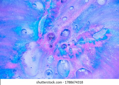 Beautiful bath bomb dissolves in blue and pink colors in the water.