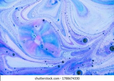 Beautiful bath bomb dissolves in blue, purple and pink colors in the water. Flat lay, top view, directly above. Abstract art