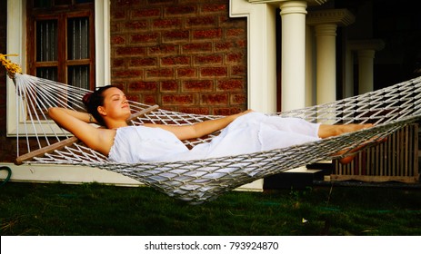 Beautiful Beach House With A Hammock Nearby. Beach Hut With A Thatched Roof. Small Yard. Perfect Option For Romantic Holidays. Young Girl Laying On The Hammock. Time To Relax, Meditation.