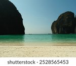 A beautiful beach with a large body of water in the background. The water is calm and clear, and the sky is blue. The beach is empty, and there are no people visible. The scene is peaceful and serene