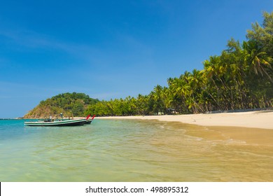 Beautiful beach of Ngapal with fisherman boat and palms hanging over the seai, Myanmar