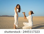 A beautiful beachside marriage proposal surprise at sunset: a romantic gesture of affection and commitment by a loving couple on the sandy shoreline