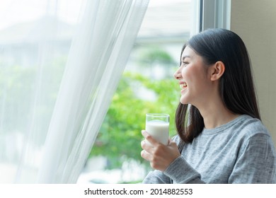 Beautiful beauty Asian woman  cute girl feel happy drinking milk for good health in the morning , enjoying time in her home white bedroom background - lifestyle beauty woman concept