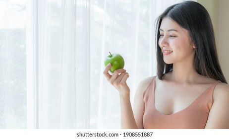 Beautiful beauty sexy Asian woman slim holding green apple on white bedroom background - lifestyle Woman diet weight loss concept 