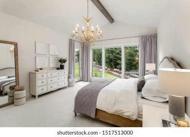 Beautiful Bedroom In New Luxury Home. Features Chandelier, Wood Beam On Ceiling, And Wall Of Windows. 