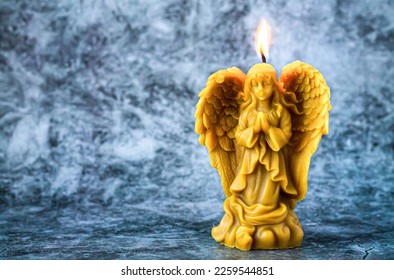 Beautiful beeswax praying angel candle on stone background. Selective focus