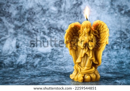 Beautiful beeswax praying angel candle on stone background. Selective focus