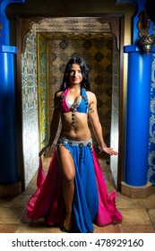 Beautiful belly dancer young woman in gorgeous pink and blue costume dress. Beautiful brunette with an excellent figure and body plastics