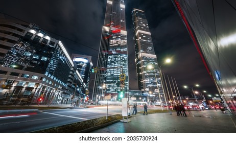 Beautiful big city busy street in the night. Modern skyscrapers glitter with neon lights, heavy traffic passing by and pedestrians crossing the intersection in the center of Moscow
