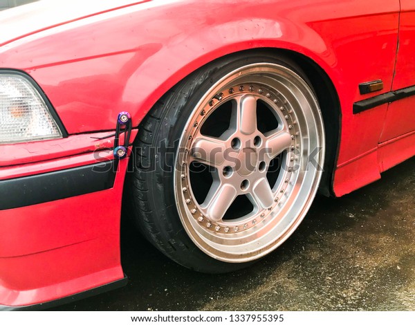 Beautiful big racing wheels of a\
sports red car with a very low ground clearance on cast shiny\
expensive alloy wheels in the style of Stans. Tuning\
cars.