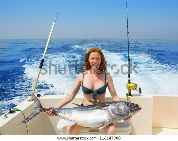 beautiful bikini fisher woman holding big bluefin\
tuna catch on boat\
deck