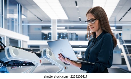 Beautiful Biotechnology Engineer Using Laptop Computer, Analyzing Robotic Machine Concept in a High Tech Factory. Female Scientist Manipulate and Program the Robot for Work. - Powered by Shutterstock