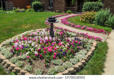 beautiful bird bath in front yard surrounded by pink and flowers in summer