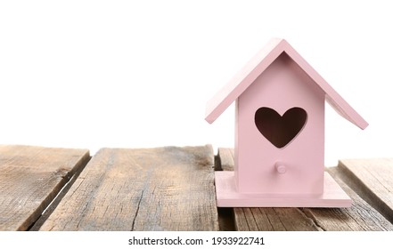 Beautiful bird house with heart shaped hole on wooden table against white background, space for text