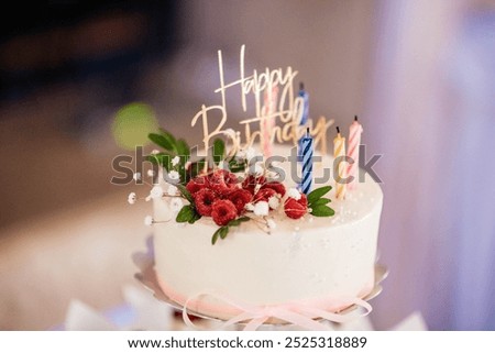Beautiful birthday cake with colorful birthday candles and raspberries. Cake for the holiday. 