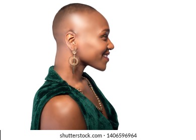 Beautiful black African American female model posing confidently with bald hairstyle on a white background.  The woman is portraying uniqueness and individuality.  