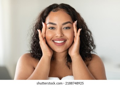 Beautiful Black Body Positive Woman Touching Her Face And Smiling At Camera, Making Beauty Treatments At Home. Young African American Lady Enjoying Selfcare