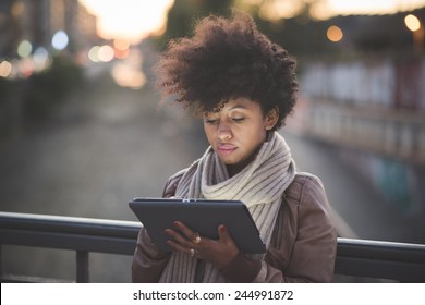 beautiful black curly hair african woman using tablet in town by night