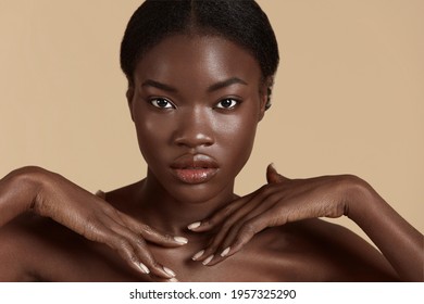 Beautiful black girl. Fashion woman with clean face looking at camera. Concept of face skin care. Isolated on beige background. Studio shoot