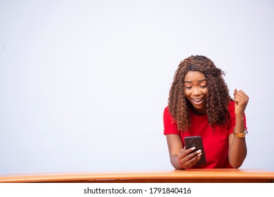 a beautiful black girl feeling excited while viewing something on her phone