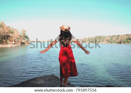 Beautiful black hair woman enjoying on the stone patio in front of lake. Pretty girl relaxing outdoor. beauty of nature. Relax time on holiday concept travel.