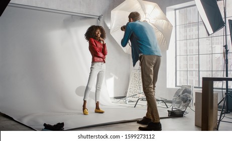 Beautiful Black Model Posing for a Photographer, he Takes Pictures with Professional Camera. She plays with Facial Expressions. Stylish Fashion Magazine Photo Shoot done in a Studio.
