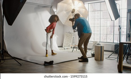 Beautiful Black Model Posing for a Photographer, he Takes Pictures with Professional Camera. She plays with Facial Expressions. Stylish Fashion Magazine Photo Shoot done in a Studio. - Powered by Shutterstock