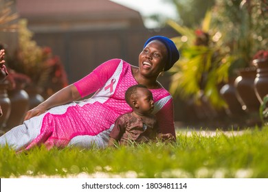 Beautiful Black Mother With Child Wearing African Costume With Pink Ribbon Craft On Her Chest For Breast Cancer Campaign-concept On Maternal Breast Cancer Awareness