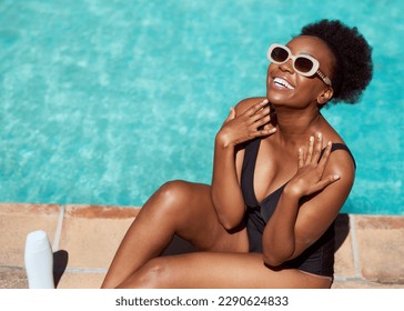 Beautiful Black woman applies sunscreen sitting by pool in summer sun - Powered by Shutterstock