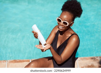 Beautiful Black woman applies sunscreen sitting by pool in summer sun - Powered by Shutterstock