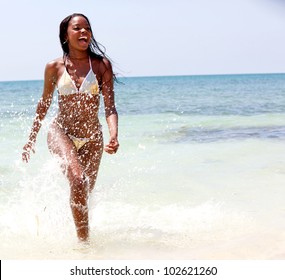 Beautiful black woman in bikini walking at the beach