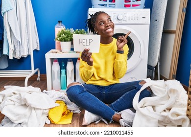 Beautiful Black Woman Doing Laundry Asking For Help Smiling Happy Pointing With Hand And Finger To The Side 