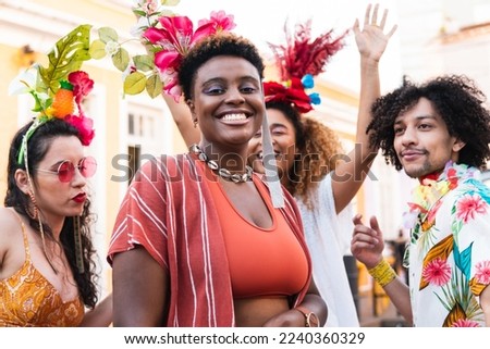 Beautiful black woman enjoying street carnival with friends. People dancing and celebrating brazilian Carnaval.