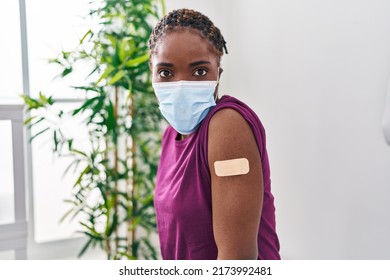 Beautiful Black Woman Getting Vaccine Showing Arm With Band Aid Scared And Amazed With Open Mouth For Surprise, Disbelief Face 