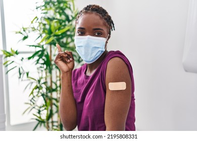 Beautiful Black Woman Getting Vaccine Showing Arm With Band Aid Smiling Happy Pointing With Hand And Finger To The Side 