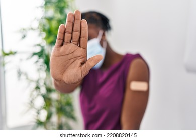 Beautiful Black Woman Getting Vaccine Showing Arm With Band Aid With Open Hand Doing Stop Sign With Serious And Confident Expression, Defense Gesture 