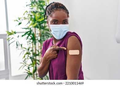 Beautiful Black Woman Getting Vaccine Showing Arm With Band Aid Smiling Happy Pointing With Hand And Finger 