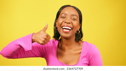 Beautiful Black woman gives thumbs up, yellow studio background - Shutterstock ID 2364727709