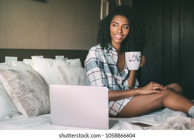 Beautiful Black Woman On Bed With Laptop And Cup Of Coffee