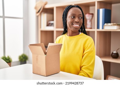 Beautiful Black Woman Opening Cardboard Box Looking To Side, Relax Profile Pose With Natural Face And Confident Smile. 