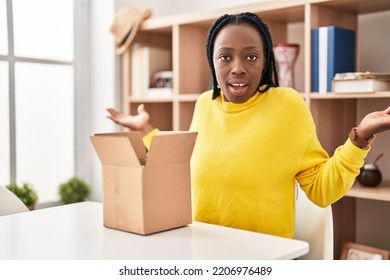 Beautiful Black Woman Opening Cardboard Box Shouting And Screaming Loud To Side With Hand On Mouth. Communication Concept. 