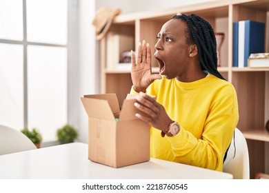 Beautiful Black Woman Opening Cardboard Box Clueless And Confused With Open Arms, No Idea And Doubtful Face. 